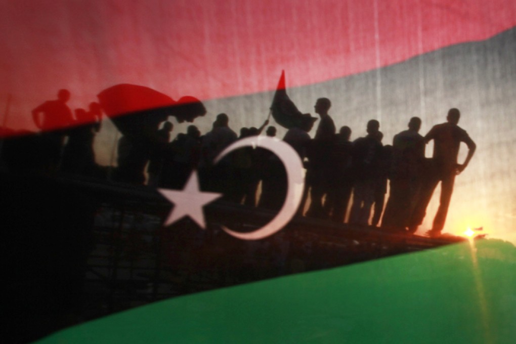 People seen behind a Libyan flag. Photo: Reuters