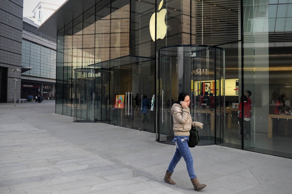 A woman uses a mobile phone as she walks past an Apple store in Beijing on January 17, 2014.Photo: AFP