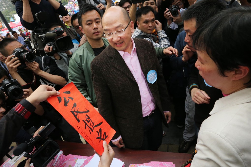 A protester gives constitutional affairs minister Raymond Tam a couplet containing a call for public nomination. Photo: Nora Tam