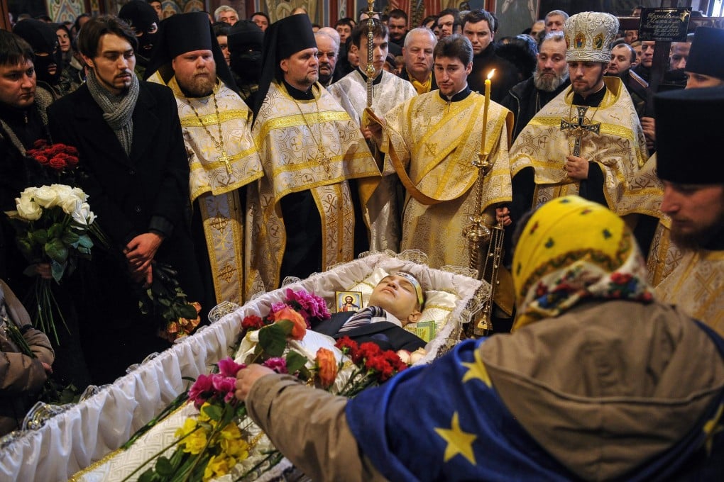 Orthodox clergymen, relatives and friends stand near the coffin of Mikhail Zhiznevsky, killed in unclear circumstances during anti-government protests. Photo: EPA