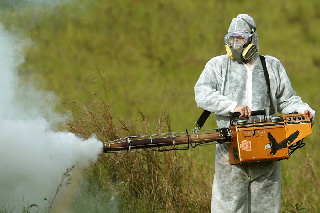 A pest control officer dressed in protective gear sprays pesticide. Photo: David Wong