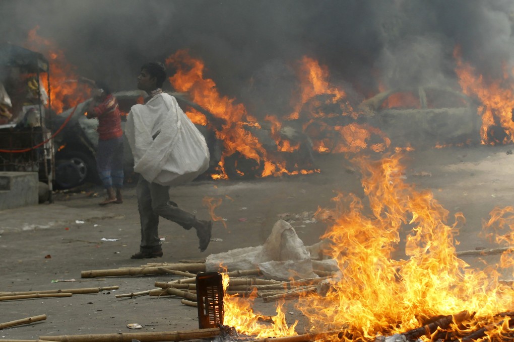 A man walks past vehicles that were set on fire by Bangladesh's Jamaat-e-Islami party activists during clashes with police in Dhaka. Motiur Rahman Nizami, leader of the party, was sentenced to hang after being convicted over a massive arms smuggling racket. Photo: Reuters