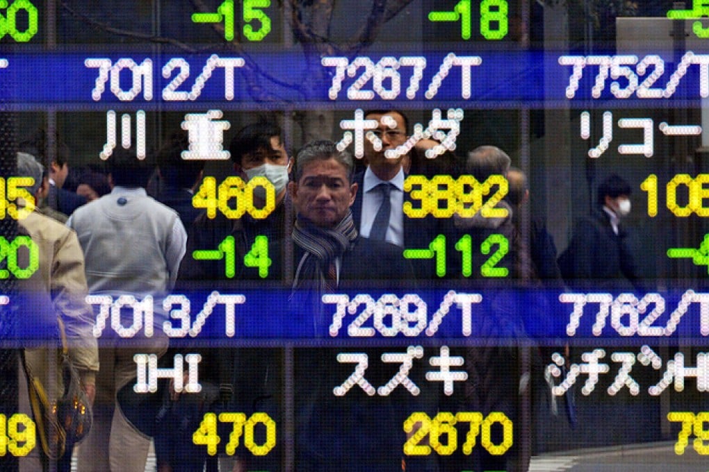 Pedestrians are reflected on a share prices board in Tokyo on Thursday. Photo: AP