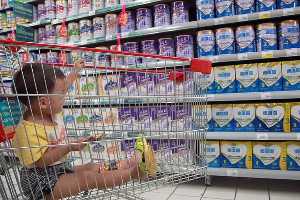A baby watches as his mother selects milk powder in a supermarket in Haikou, Hainan province. Photo: AFP