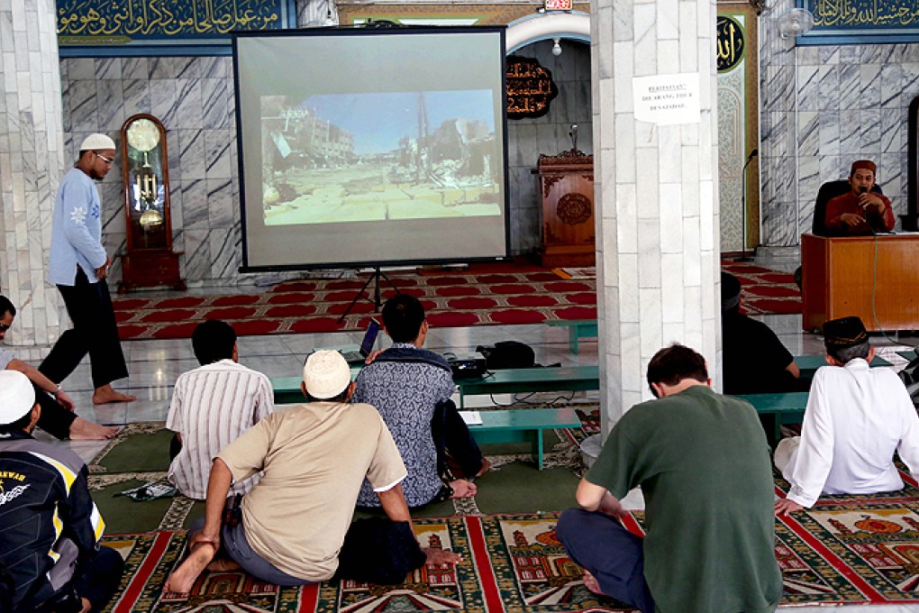 Muslim men watch a slideshow from Syria during a prayer calling for jihad at a mosque in Jakarta. Photo: AP