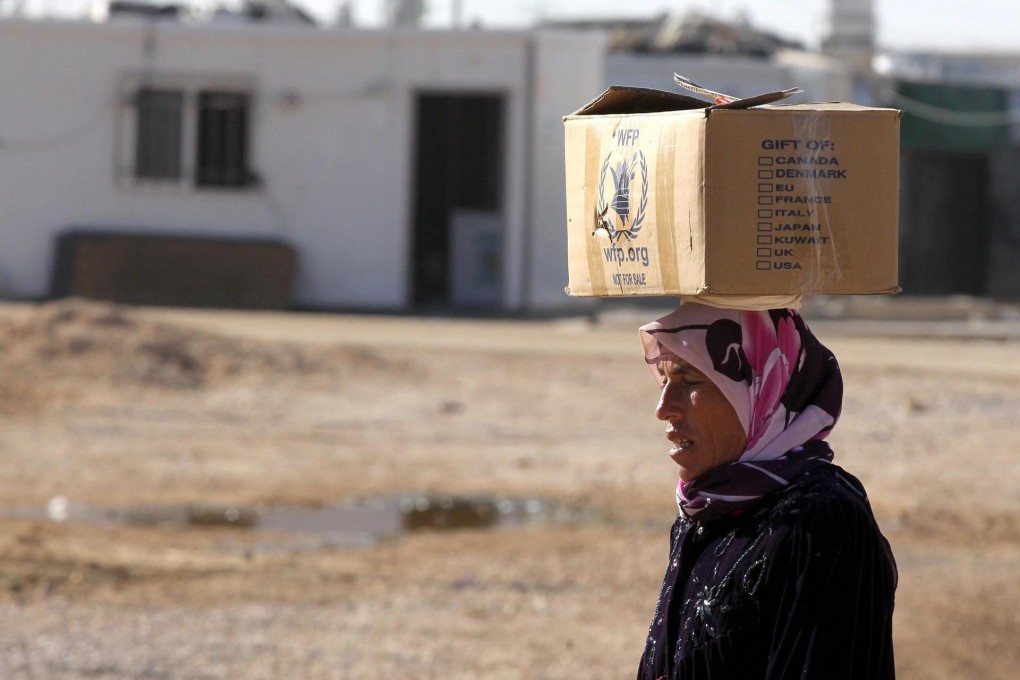 A Syrian refugee carries a box of food from WFP. Photo: EPA