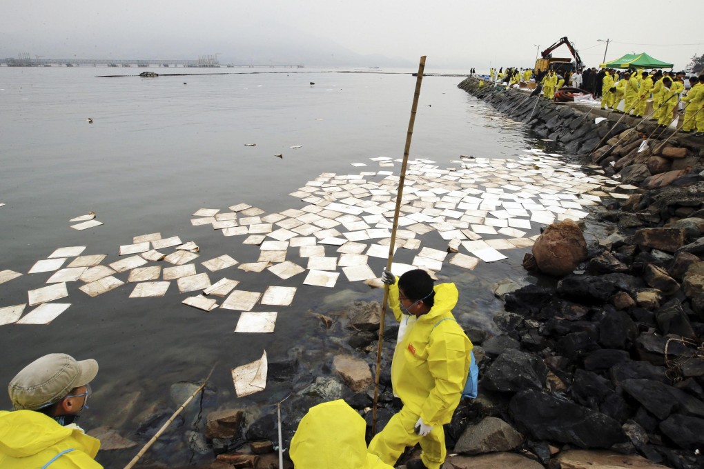 Workers remove crude oil spilt over a port in Yeosu, about 460km south of Seoul. Photo: Reuters