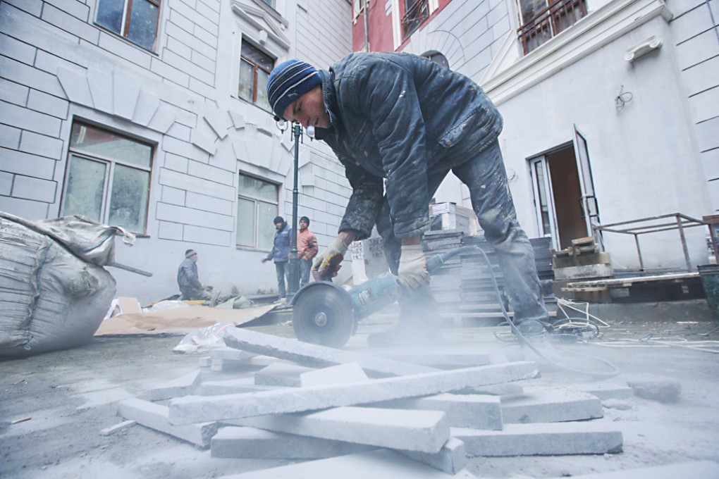 A worker cuts stone in front of accommodation for the Sochi 2014 Winter Olympics. Photo: AP