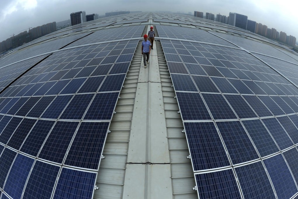 Workers walk between solar panels on the roof of Hangzhou East railway station in Zhejiang province. Photo: AP