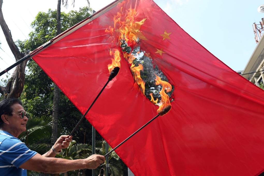 Filipino retired police officer and former town mayor Abner Afuang burns a Chinese flag, in protest over territorial disputes at a shoal in the South China Sea. Photo: EPA