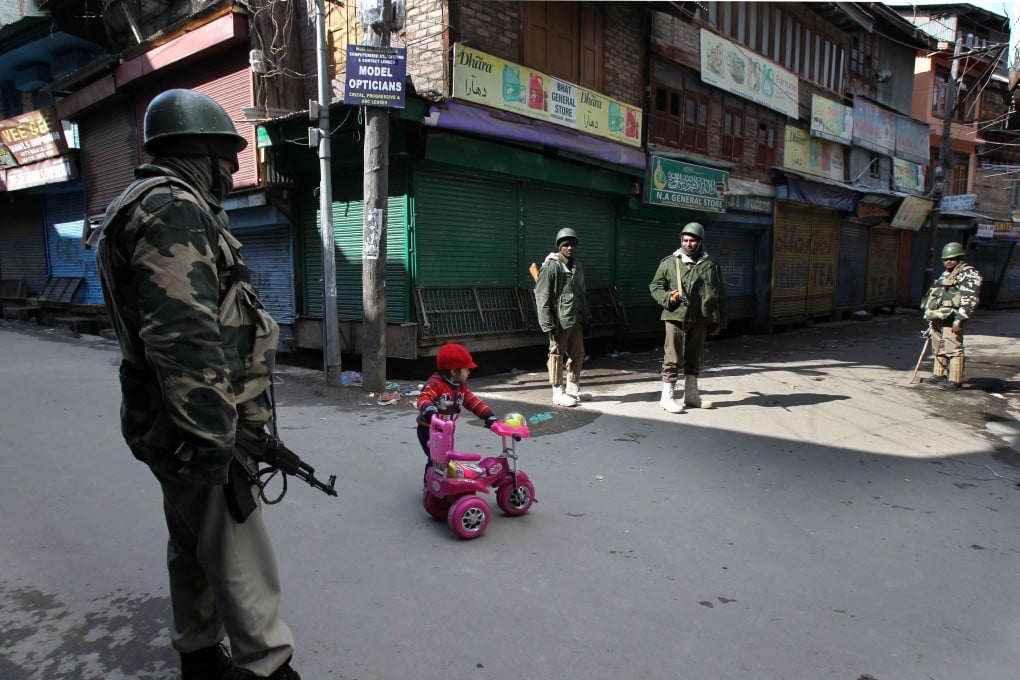 A Kashmiri child plays with his tricycle as Indian paramilitary troopers stand guard in a closed market during a curfew in Srinagar, the summer capital of Indian-controlled Kashmir. Photo: Xinhua