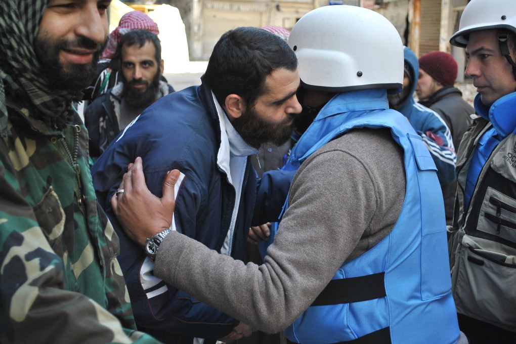 Members of a United Nations and Syria's Red Crescent convoy are welcomed by rebel fighters after entering a besieged district of the central city of Homs. Photo: AFP