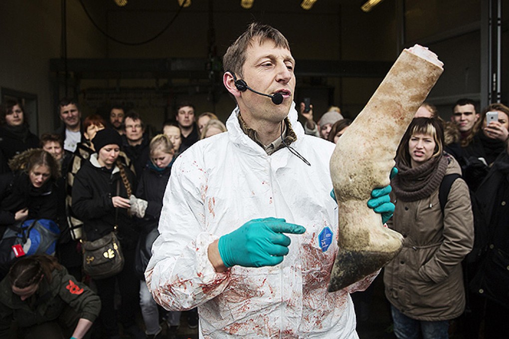 People look on as a veterinarian holds a leg of the giraffe Marius while it was being dismembered in Copenhagen Zoo. Photo: Reuters
