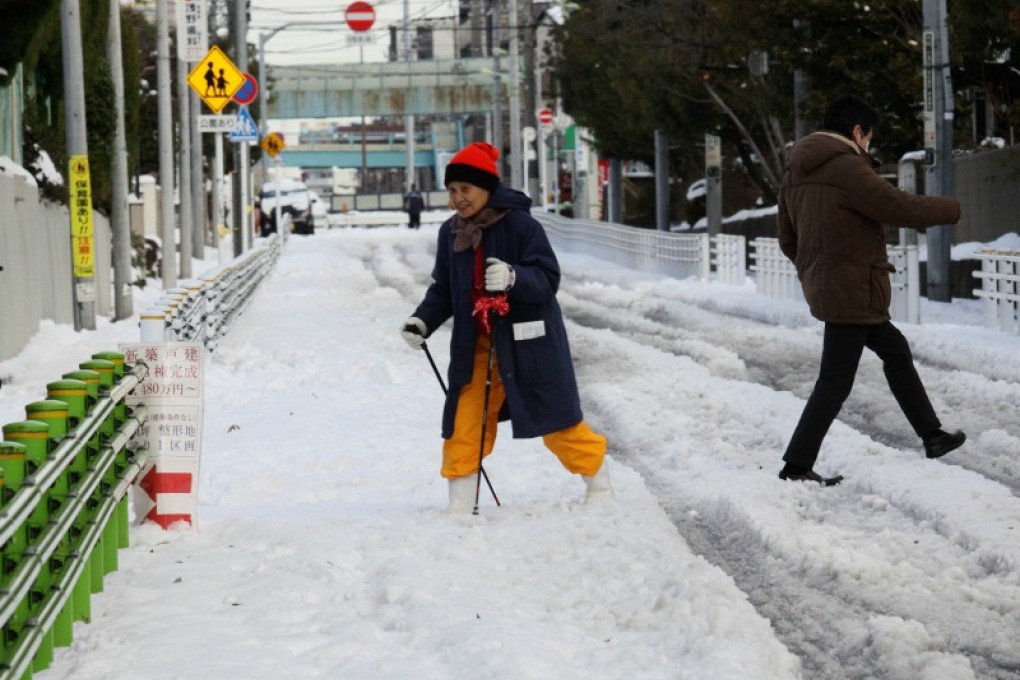 A woman walks with sticks on a snow covered road in Tokyo. Photo: AFP