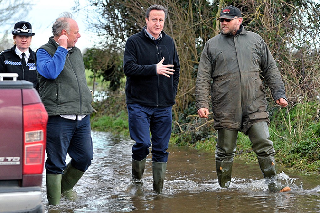 British Prime Minister David Cameron (centre) talks to Bridgwater and West Somerset MP Ian Liddell-Grainger (left) and farmer Tony Davy (right) during a visit to flooded areas. Photo: EPA