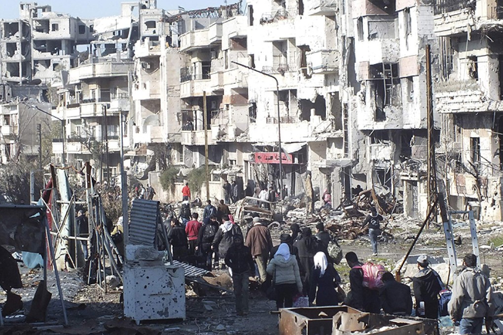 Civilians carry their belongings as they walk towards a meeting point to be evacuated from a besieged area of Homs. Photo: Reuters
