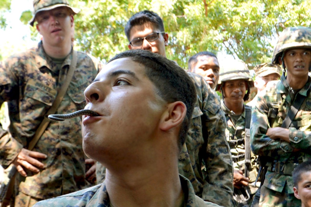 RETROSPECTIVE: A US Marine (front) plays with cobra's tail during a jungle survival programme as part of the Cobra Gold exercises at a navy base in Sattahip, Thailand, last year. This year will see some PLA soldiers join the drills. Photo: AFP