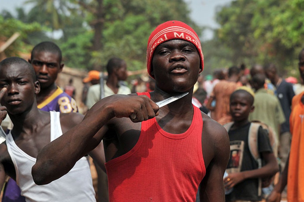 A man holds a knife to his throat claiming that he is looking for Muslims to cut off their heads in Bangui. Photo: AFP