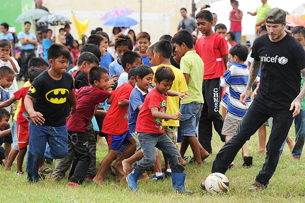 England football superstar David Beckham (right) plays football with children-survivors of super Typhoon-Haiyan at a school ground in Tanuan town, Leyte province, central Philippines on Friday. Photo: AFP