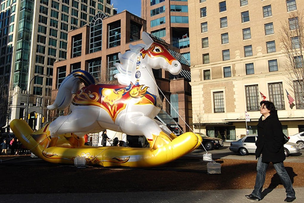 A woman walks by a giant inflatable rocking horse during the Chinese New Year in Vancouver. Photo: Xinhua