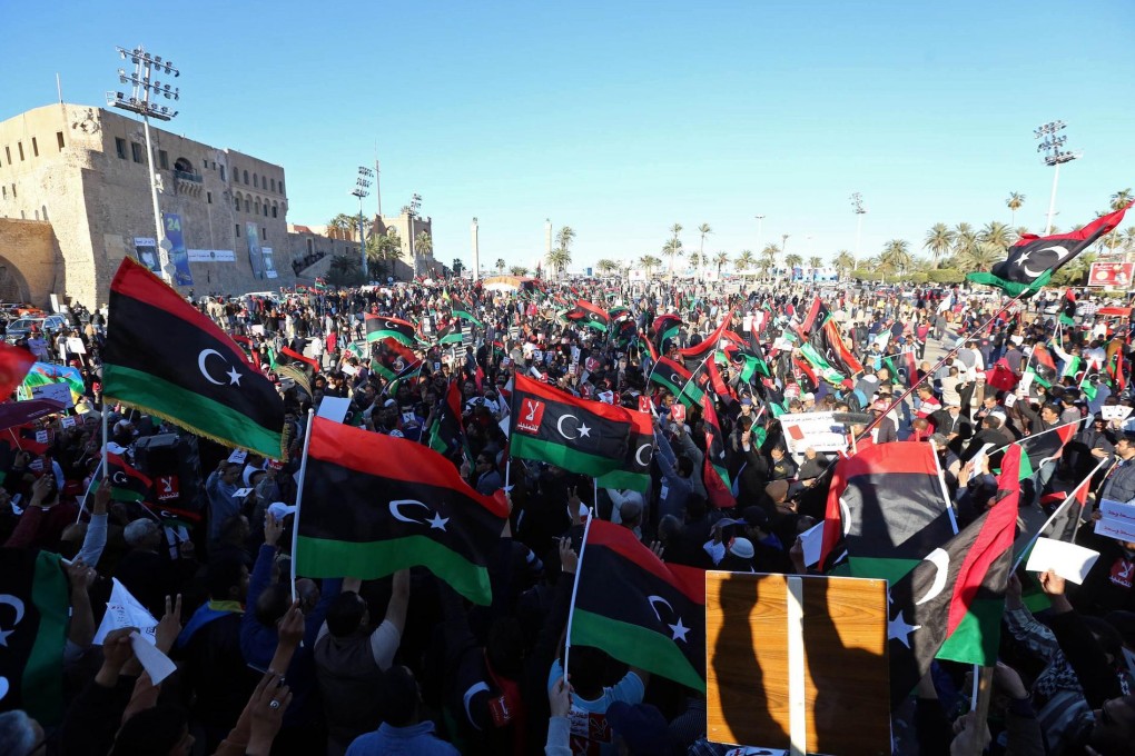 Protesters in Tripoli wave the Libyan flag as they rally against the extended mandate of the provisional government. Photo: AFP