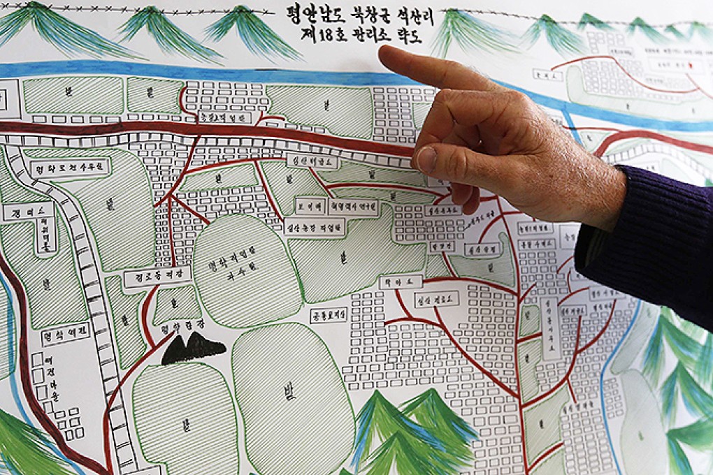 A UN Human Rights staff member points to the title of a drawing describing North Korean labour camp no 18 in Geneva. Photo: Reuters