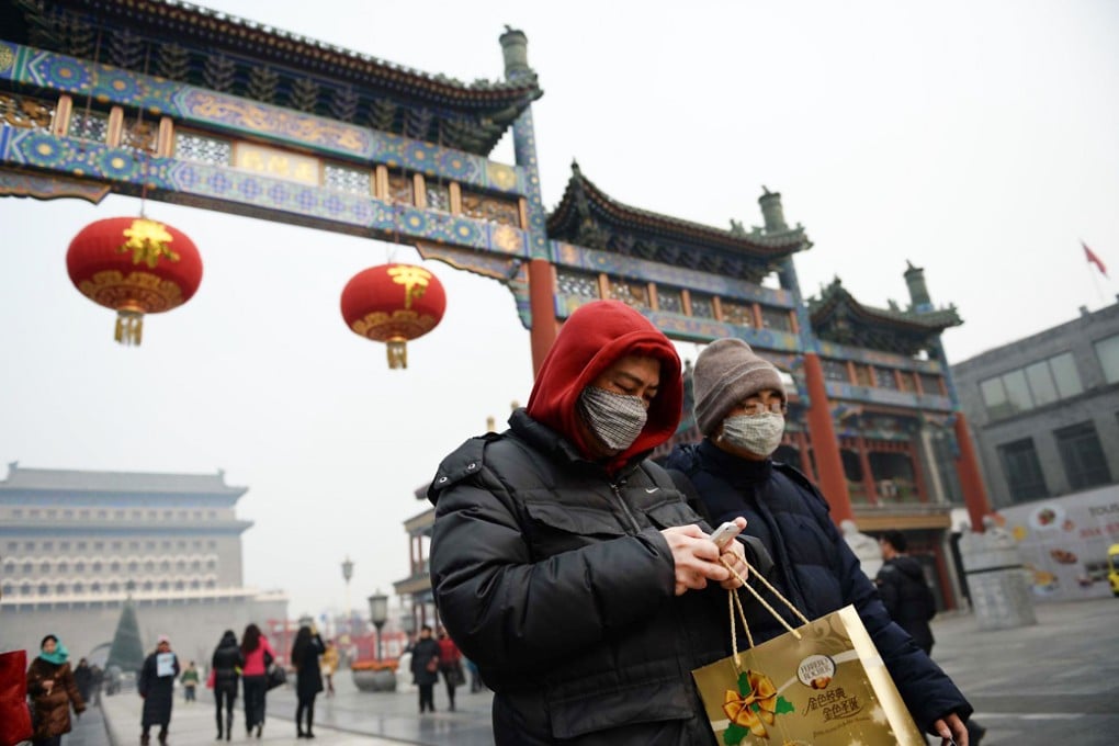 People walk along Beijing's Qianmen Street with their faces covered on Saturday as the capital coped with severe pollution. Photo: AFP