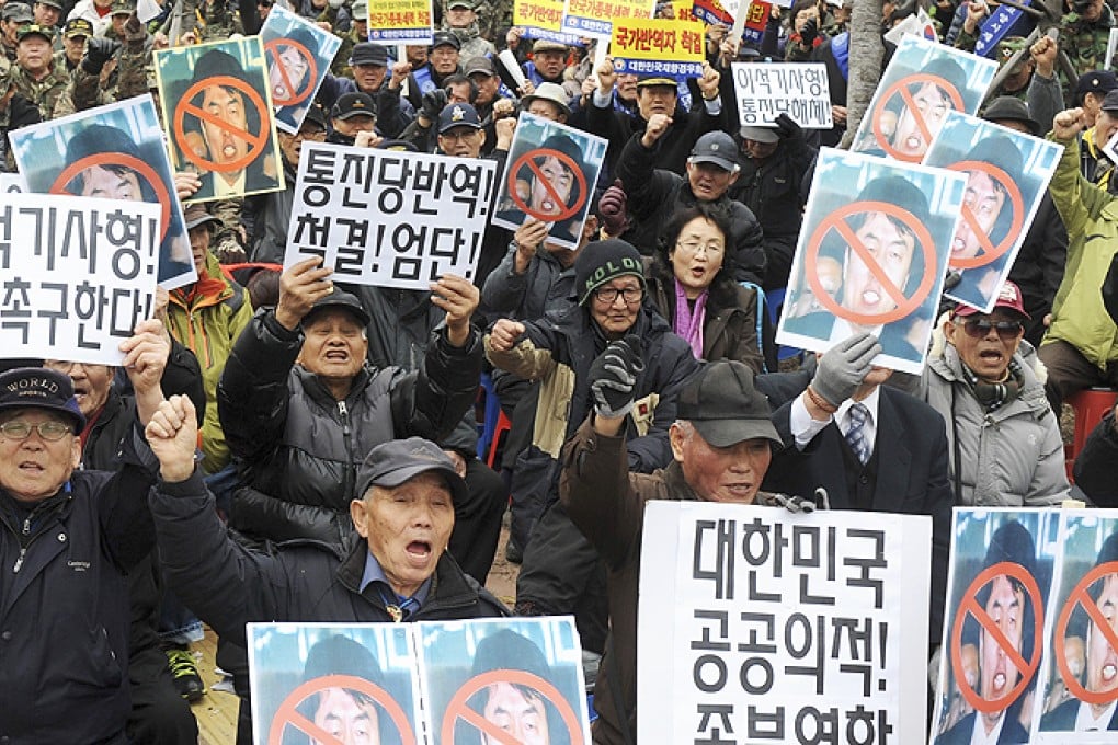 Conservative activists hold defaced photos of leftwing lawmaker Lee Seok-ki of the Unified Progressive Party while shouting slogans during a rally against Lee in front of the Suwon District Court in Suwon, South Korea, on Monday. Photo: AP