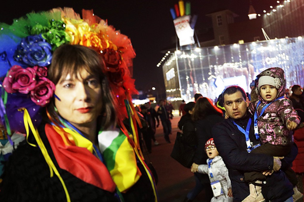 A father and children look on as Vladimir Luxuria (left) speaks out about gay rights while walking through the Olympic Plaza at the 2014 Winter Olympics, on Monday. Photo: AP