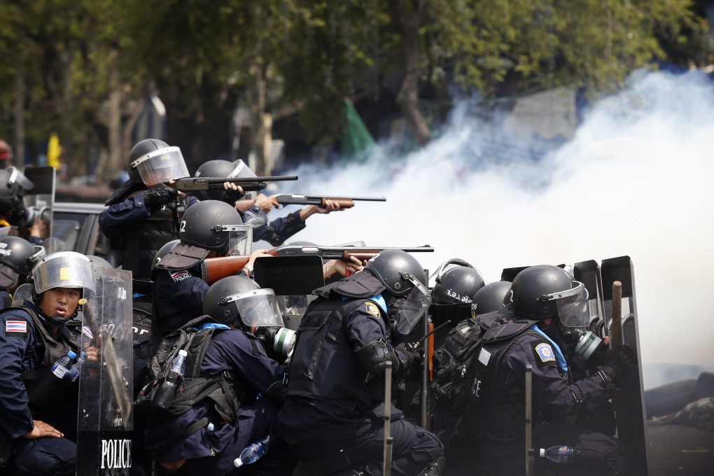 Thai policemen aim their weapons towards anti-government protesters during clashes near Government House in Bangkok. Photo: Reuters