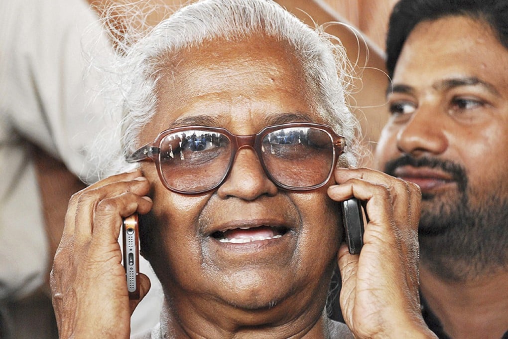 Arputhammal, mother of one of the three men convicted for involvement in the killing of former prime minister Gandhi, speaks on two mobile phones in Chennai on Tuesday. Photo: Reuters