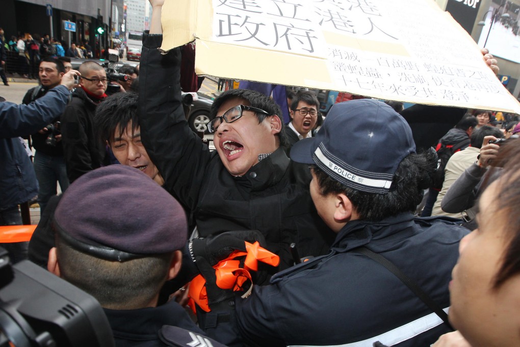 Members of local radical groups wave placards with offensive language and shout slurs at mainland Chinese tourists in Tsim Sha Tsui on Feb. 16 in Hong Kong. Photo: SCMP