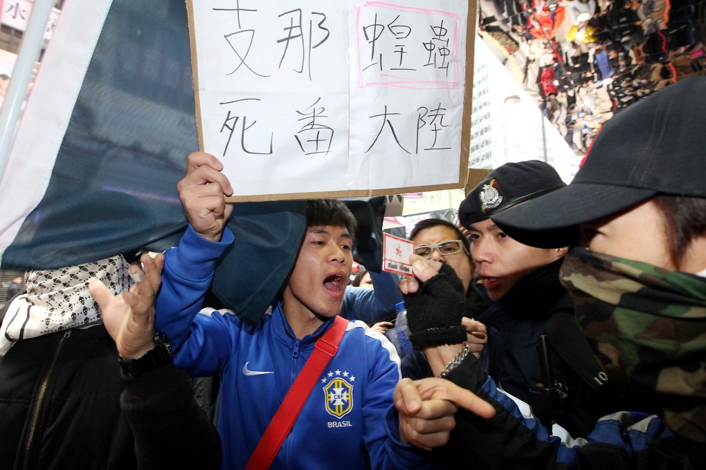 Members of radical groups hold up placards with slurs and shout abuse at mainland Chinese tourists during a protest in Tsim Sha Tsui on February 16, 2014 in Hong Kong. Photo: SCMP/Felix Wong