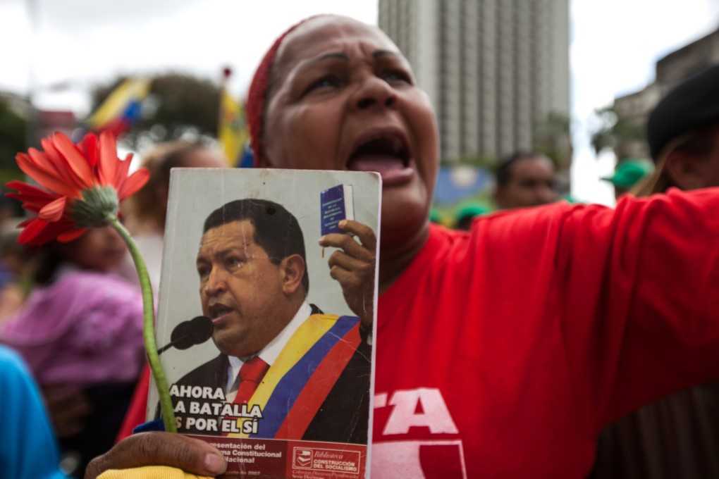 A supporter of Venezuelan President Nicolas Maduro holds a portrait of late President Chavez during a demonstration demanding peace, in Caracas, Venezuela. Photo: Xinhua