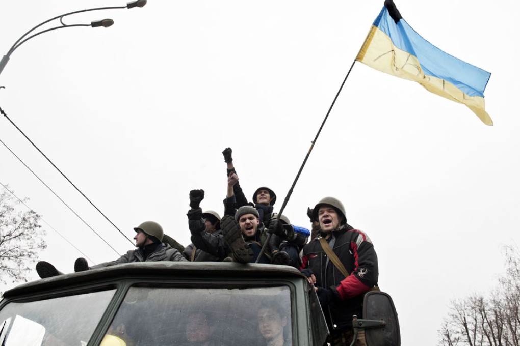Anti-government protesters in a truck cheer and wave a Ukrainian flag as they visit the residency of the deposed Ukrainian president near Kiev. Photo: AFP