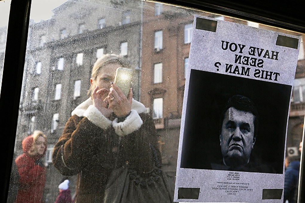 A woman takes photos of a "Wanted" notice for fugitive Ukrainian President Yanukovich near Kiev's Independence Square. Photo: Reuters