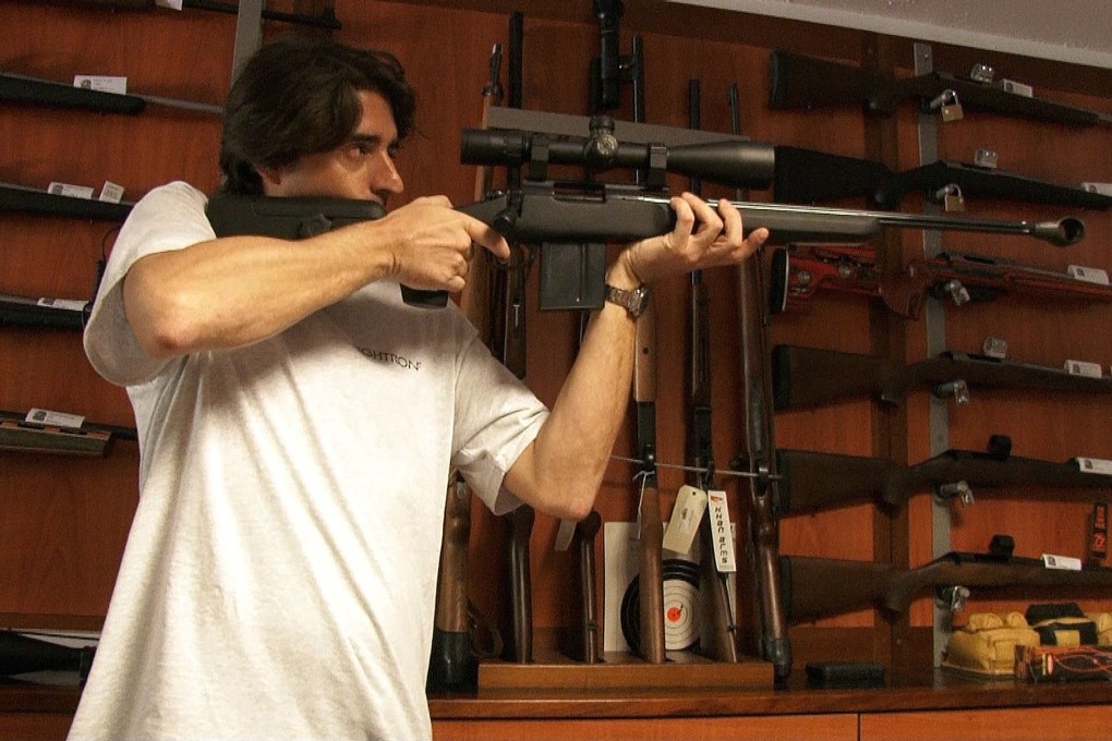Gun shop staff member Michael Bruear aims a gun behind the counter in Noumea. Photo: AFP