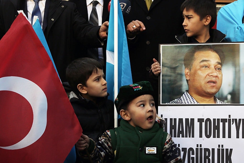 An Uygur boy holds a placard with a photo of Ilham Tohti that reads 'Freedom to Ilham Tohti' during a demonstration. Photo: AP