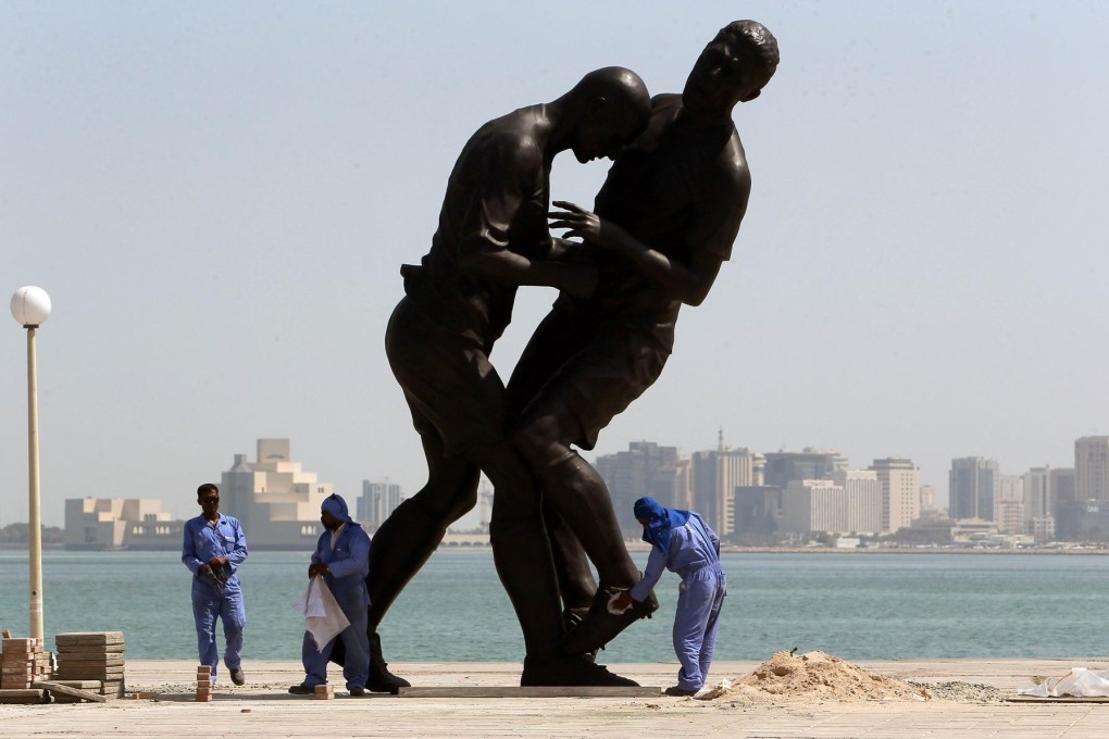 Foreign workers clean a statue in Doha, the capital of Qatar.