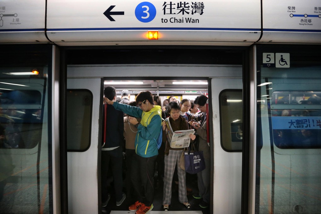 Mobile gadgets are out in force on rush-hour trains at Admiralty yesterday morning as one woman finds enough elbow room to read a newspaper. Photo: K. Y. Cheng