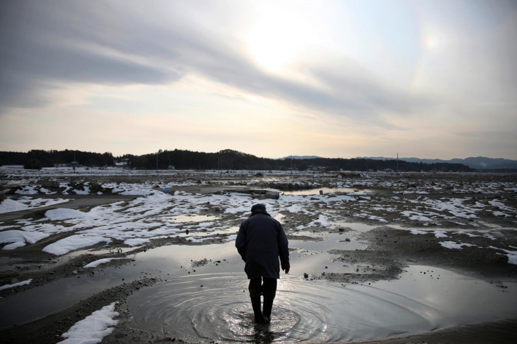 A man walks through puddles of water at the site where his house stood before the March 11 earthquake and tsunami in Fukushima. Photo: Bloomberg