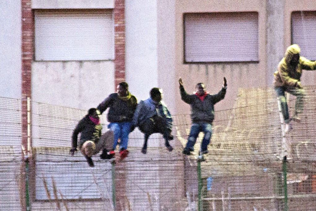 Would be immigrants jump over a fence into the north African Spanish enclave of Melilla on Friday. Photo: AFP