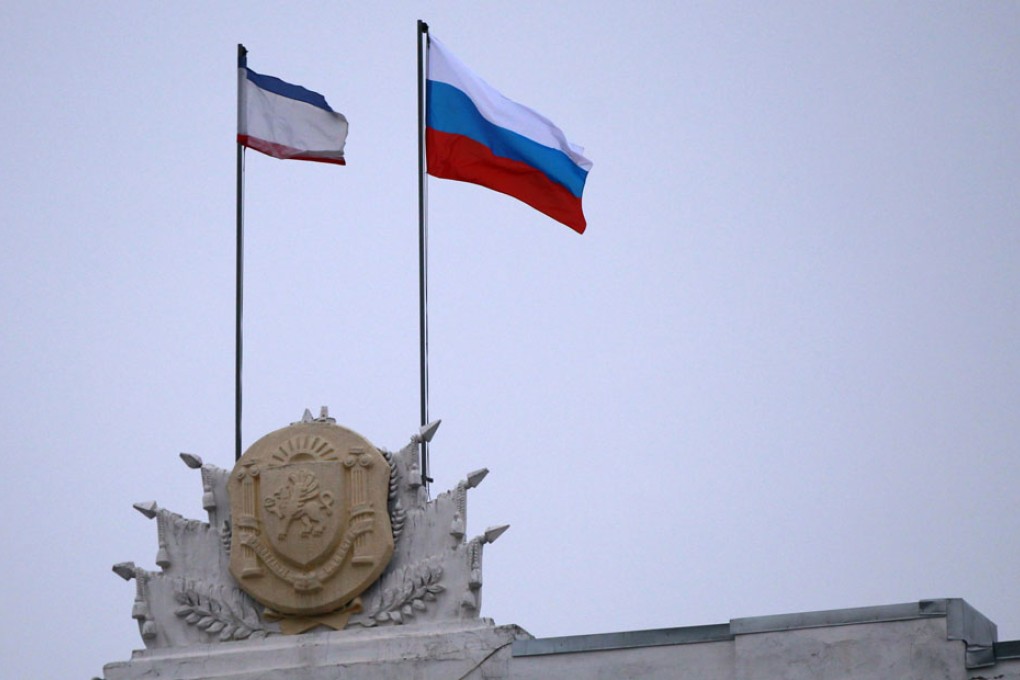 The Russian flag is raised next to the Crimean flag on top of the Crimean government building in Simferopol, Crimea. Photo: Reuters