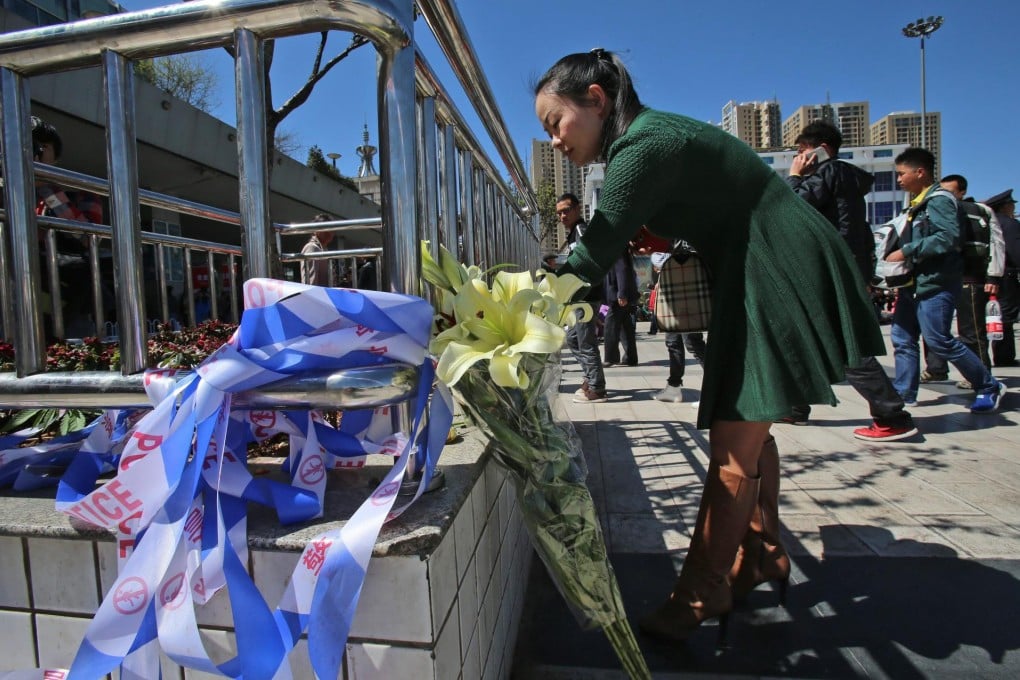 A woman places flowers for the victims along a fence outside the railway station. Photo: EPA