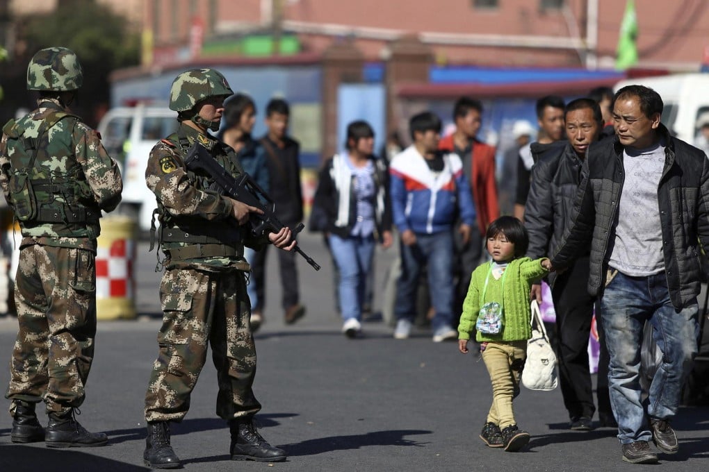A young girl looks up at two paramilitary policeman who were on patrol yesterday after the horrific attack at Kunming railway station on Saturday. Photo: Reuters
