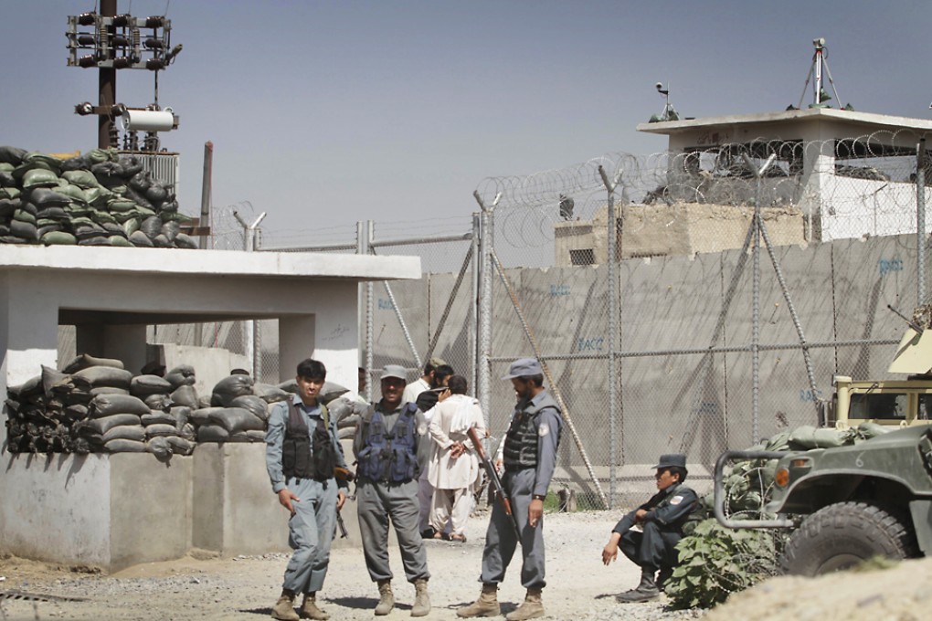 Afghan policemen stand in front of gate of the main prison in Kandahar, Afghanistan. Photo: AP