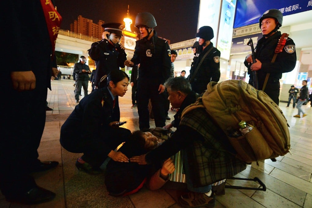 Police officers help a sick woman at the scene of the terror attack at the main train station in Kunming, Yunnan Province on March 2, 2014. Photo: AFP