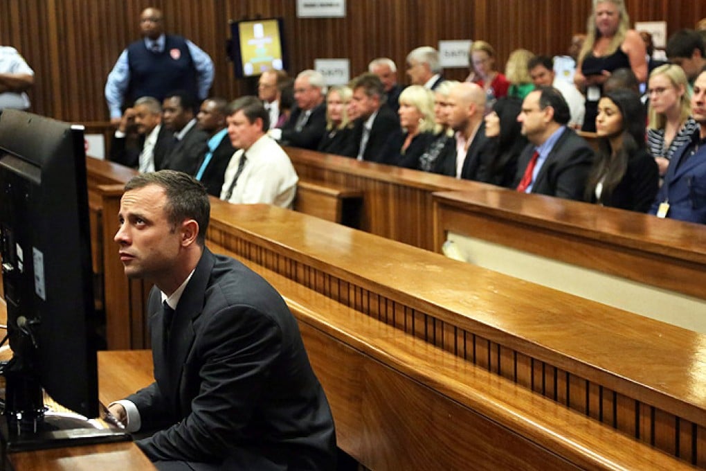 Accused South African Paralympic athlete Oscar Pistorius studies a large screen as he awaits the start of the first day of proceedings inside the high court in Pretoria, South Africa, on Monday. Photo: EPA