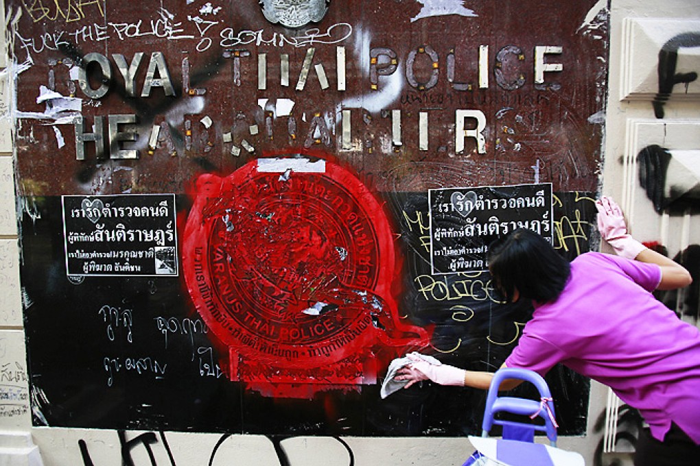 An anti-government protester volunteers to clean graffiti debris from the main gate of the Royal Thai Police Headquarters in Bangkok on Saturday. Photo: Reuters