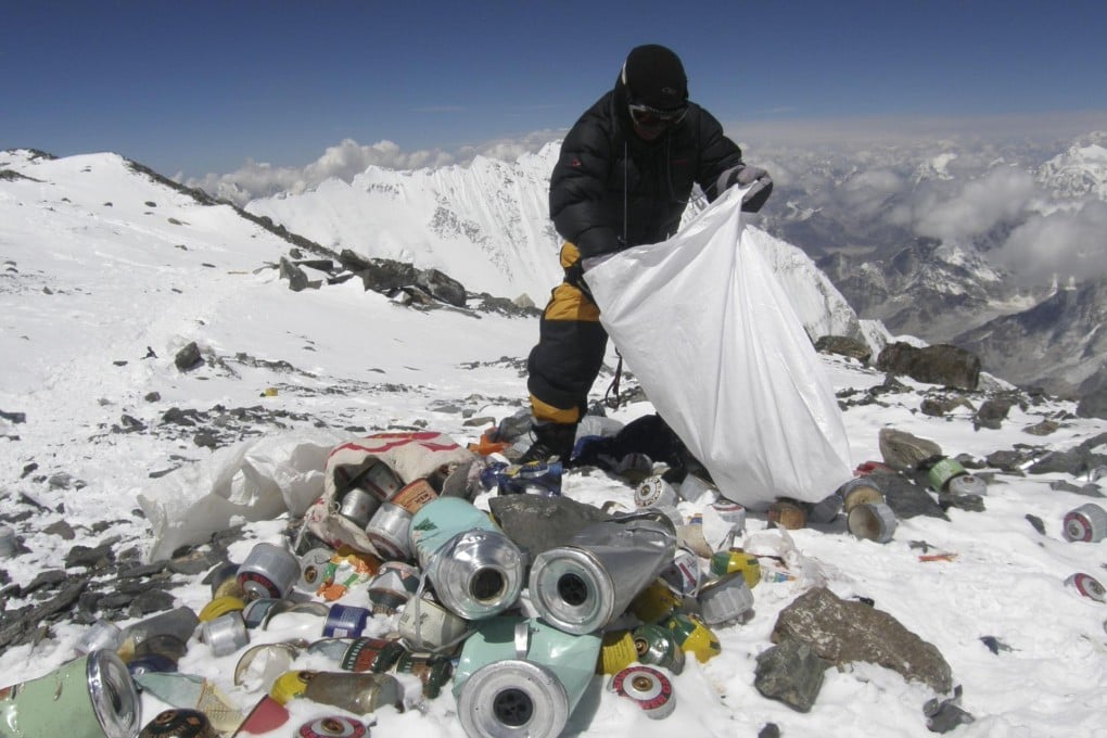 A Sherpa collects litter left 8,000 metres up Mount Everest - new rules mean climbers will now have to carry back 8kg of trash. Photo: AFP